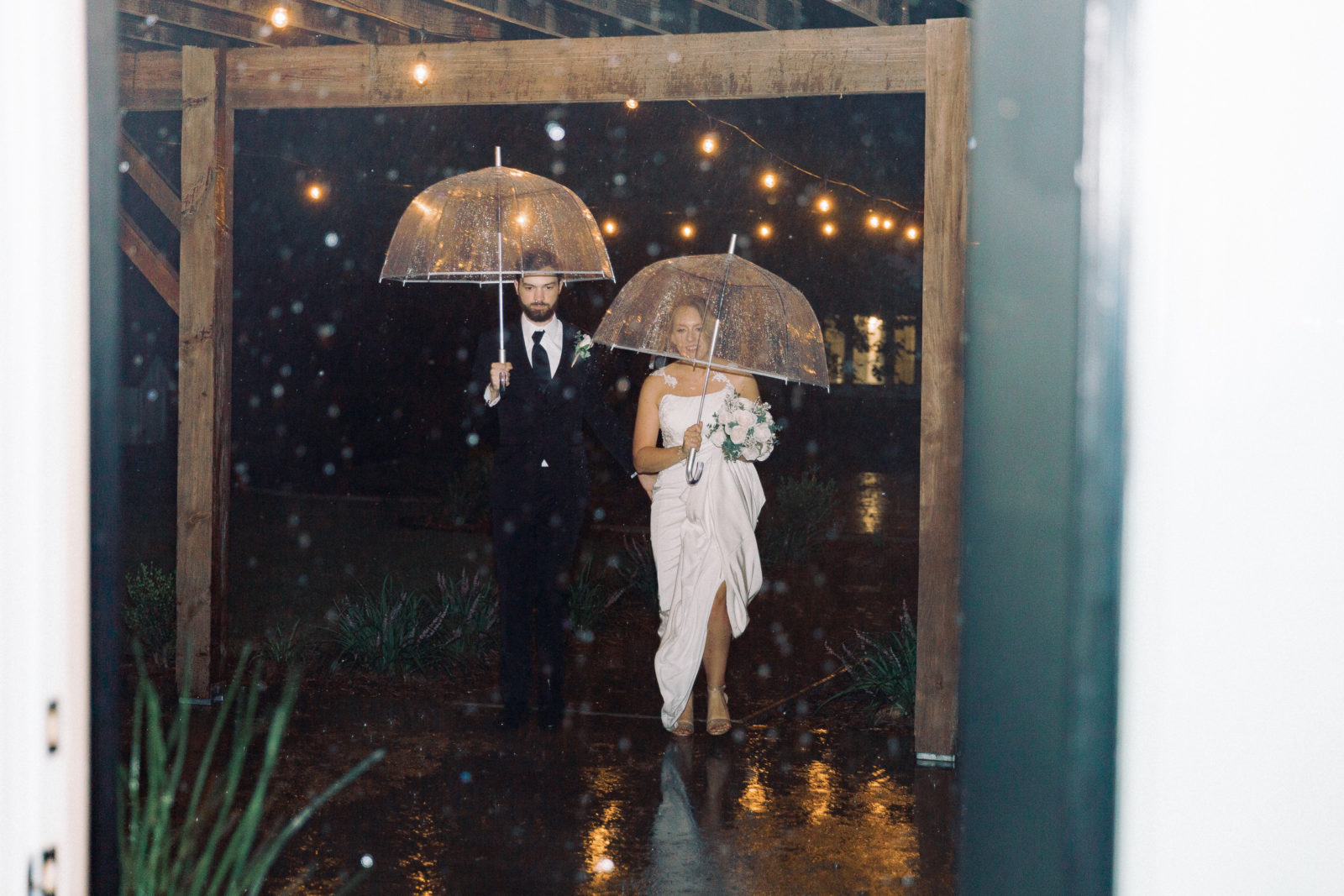 Bride and groom exit with umbrellas