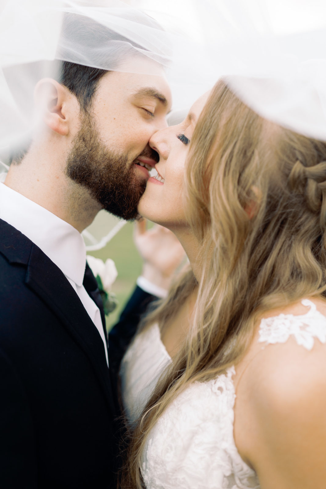 portrait of bride and groom kissing under the veil